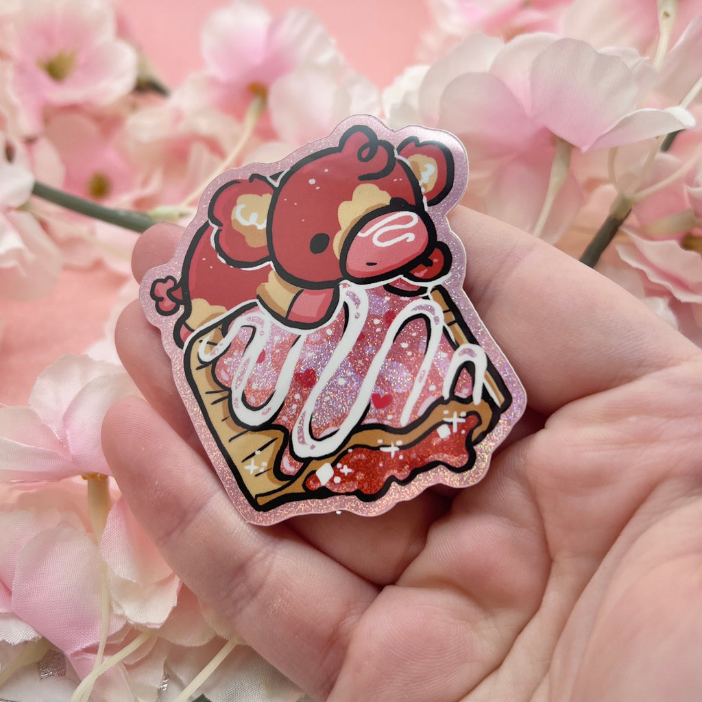 A sticker of a red and tan cow on top of a glitter pink strawberry pastry