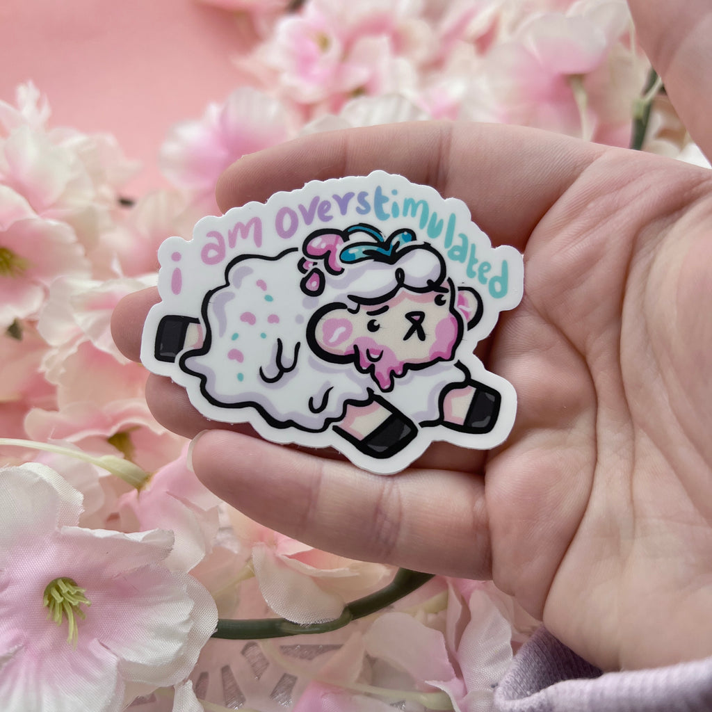 a sticker of a sheep that is slightly melting with the text "i am overstimulated" on top