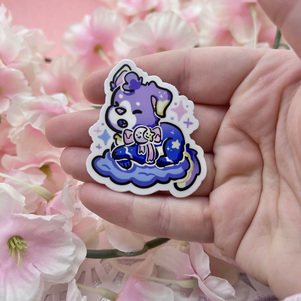 A sticker of a puppy with a purple gradient skin, moon/star bow, and is on a purple cloud.