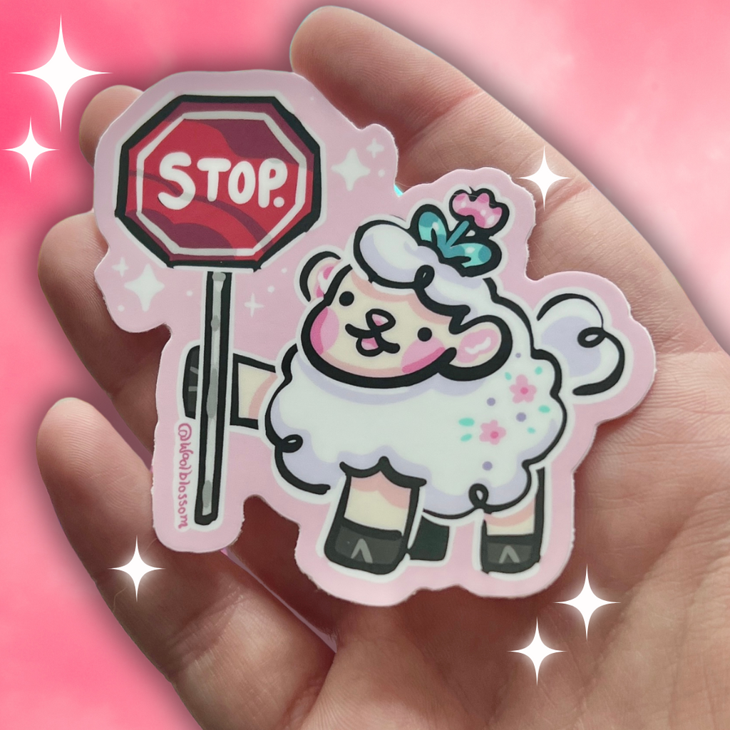 Hand holding a sticker of a sheep holding a stop sign