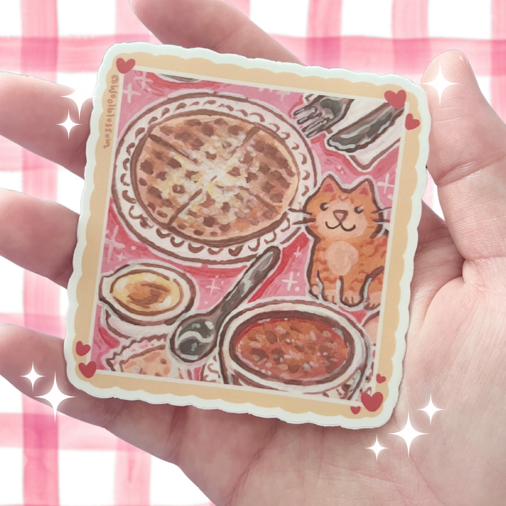 Sticker with an orange cat eating a lunch of waffle and chili held in a hand against a pink checkered background