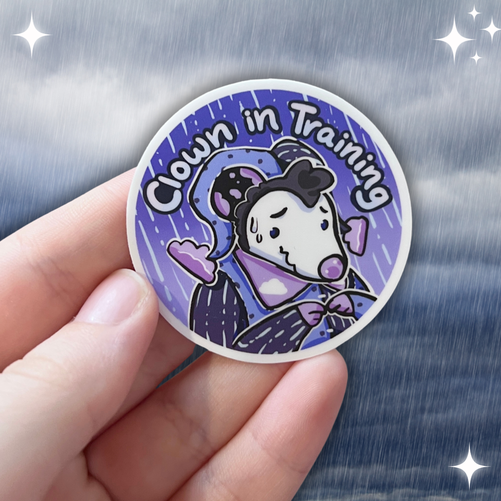 A sticker of a rain themed opossum that looks a little nervous with the text "clown in training"