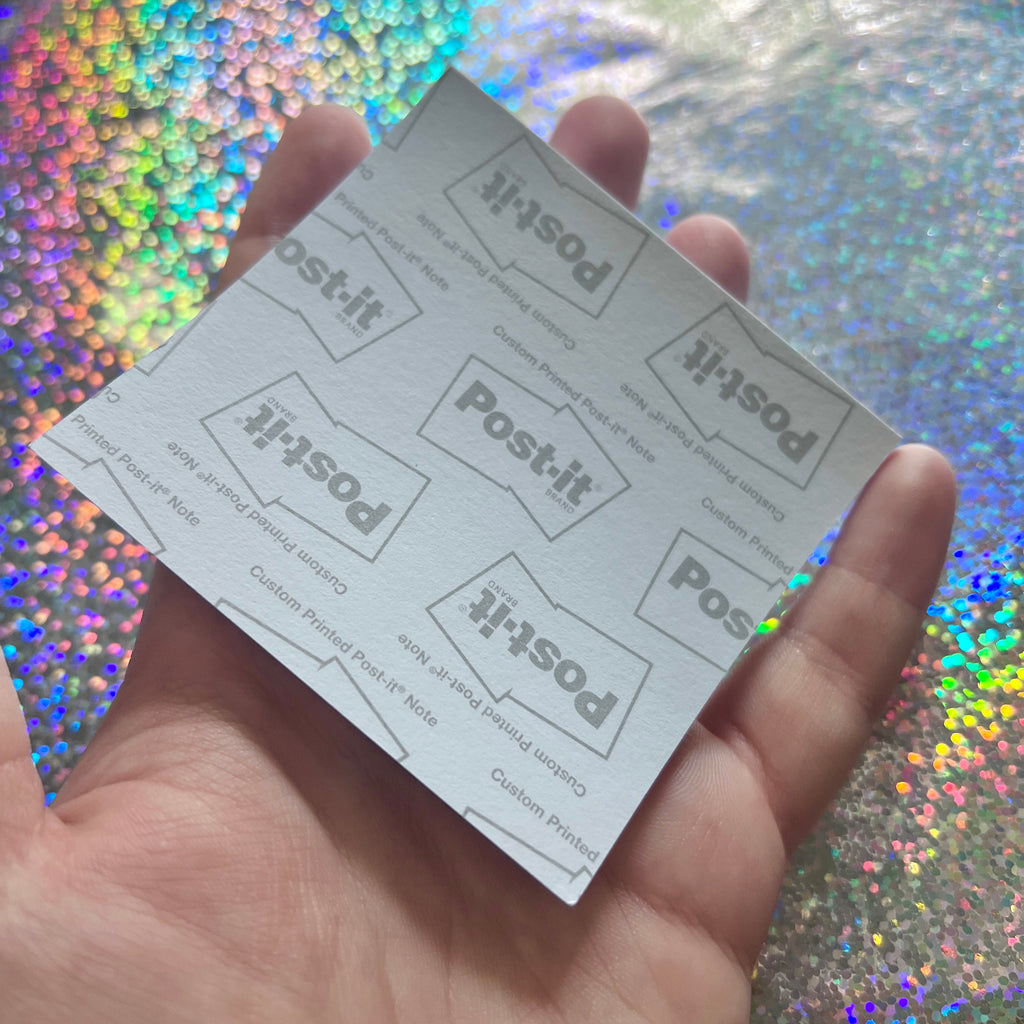 Hand holding a stack of Post-it notes against a colorful, glittery background