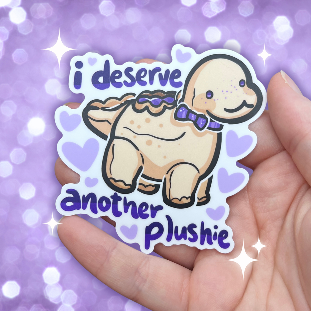 A sticker of a drawing of my old PBJ dino plushie, with text that says "I deserve another plushie