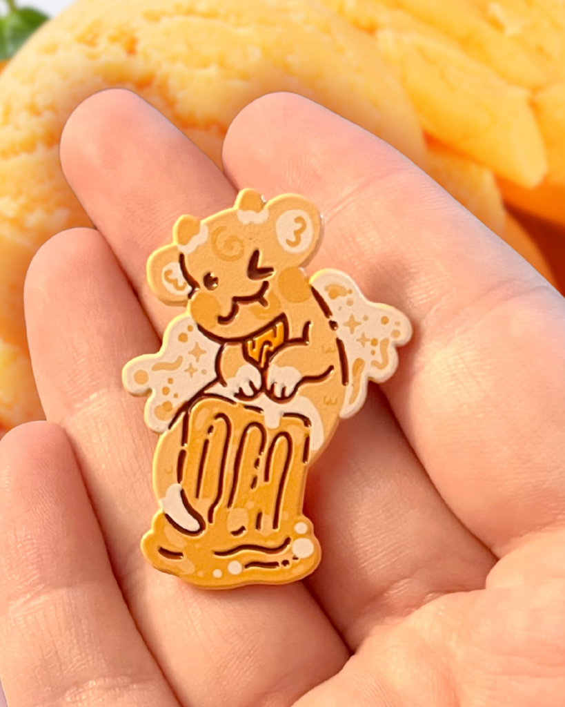 orange creamsicle dragon pin held in a hand