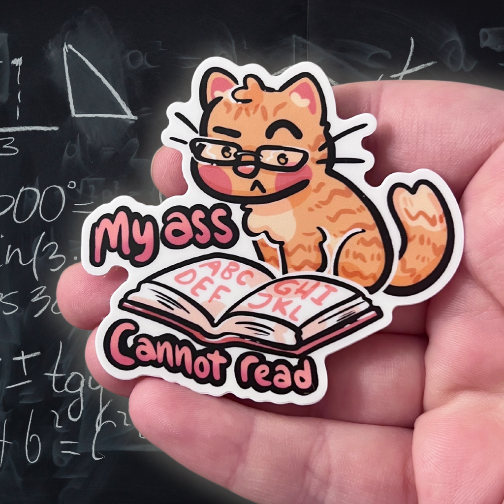 A sticker of an orange tabby cat with glasses looking inquisitively at an upside down book with text that says "my ass cannot read"