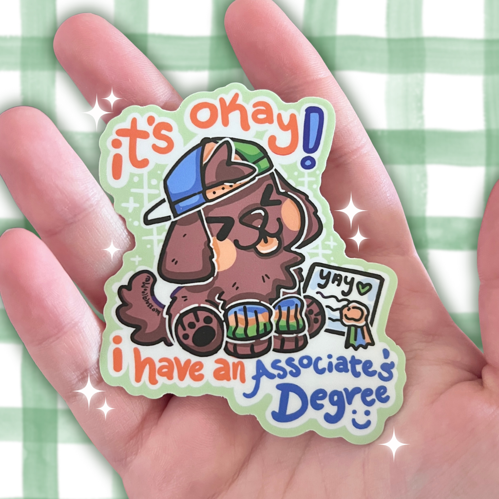 Sticker with a cartoon dog wearing a cap and glasses, text 'it's okay! yay i have an associates Degree' held in a hand against a light green checkered background.