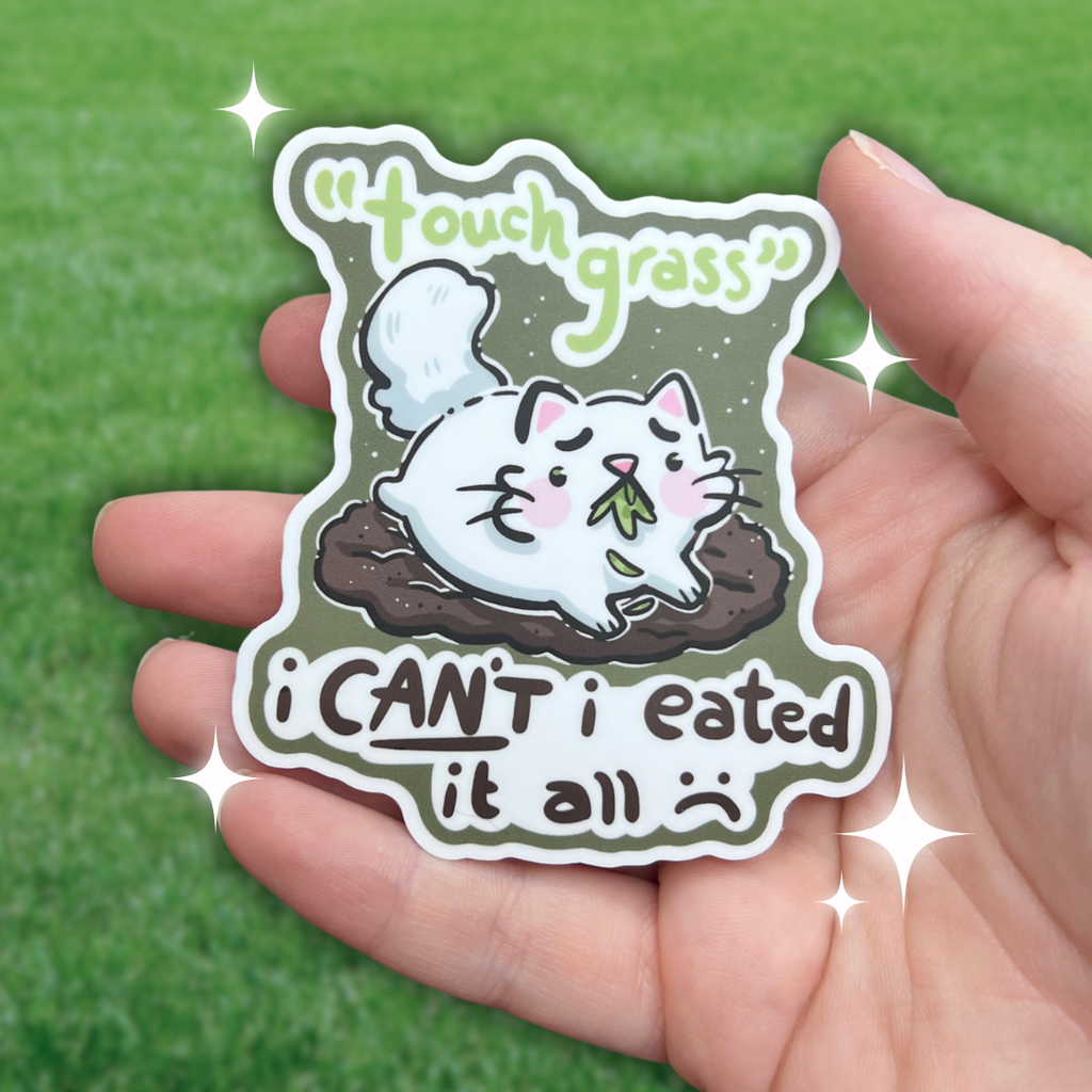 A sticker of a distressed cat laying on a bare patch of dirt, grass in her mouth with text that says "touch grass, i can't i eated it all :("