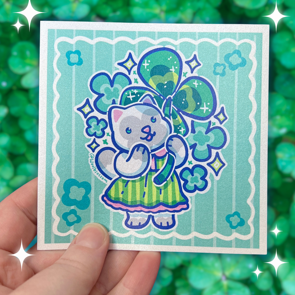 A print of a grey cat in a green stripe dress holding a four leaf clover