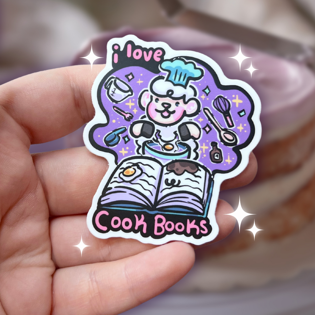 A book genre inspired sticker that says "I love cook books" and features sprout the sheep baking