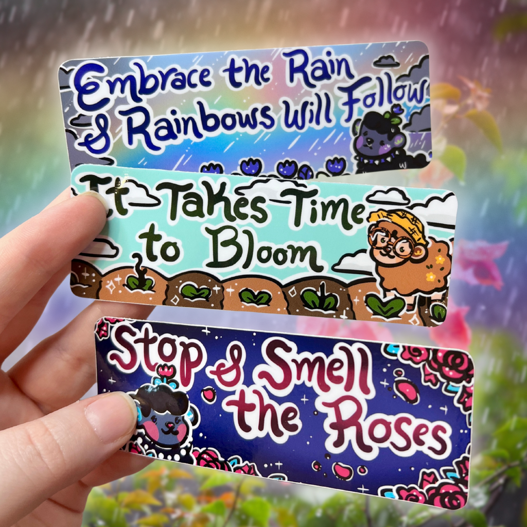 Three bumper stickers featuring a sheep in nature and 3 different sayings: "embrace the rain and rainbows will follow" "it takes time to bloom" and "stop and smell the roses"