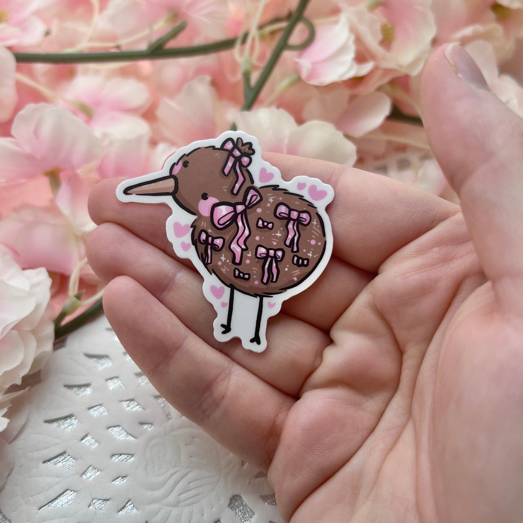 A sticker of a kiwi bird with various pink bows on it