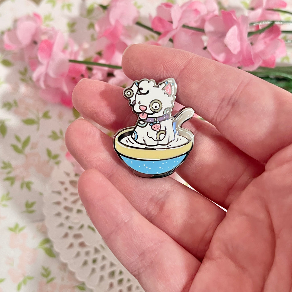 An enamel pin of a fruity cereal themed puppy sitting in a bowl of milk