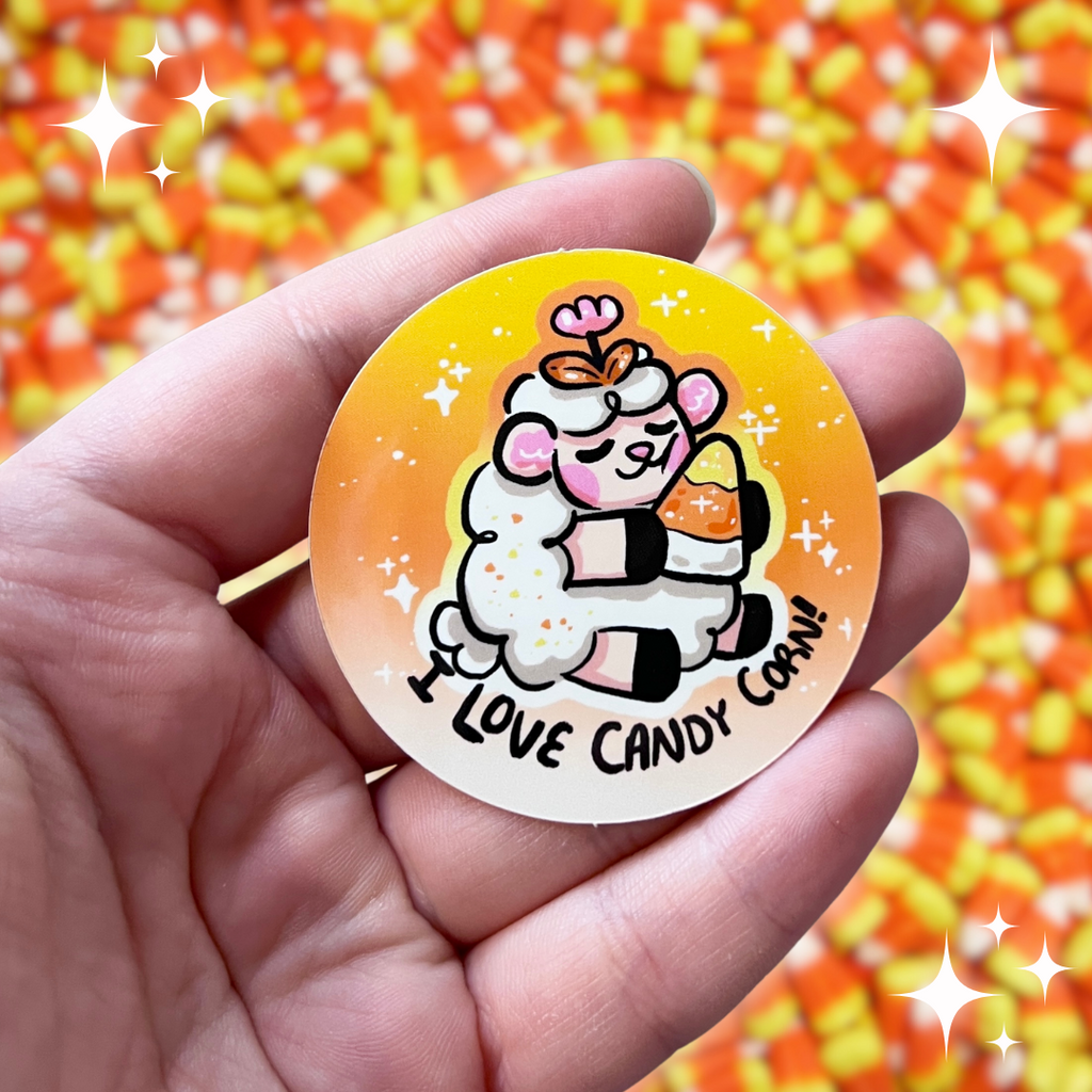 A sticker of a sheep holding a candy corn, looking content, with the text "I love candy corn!"