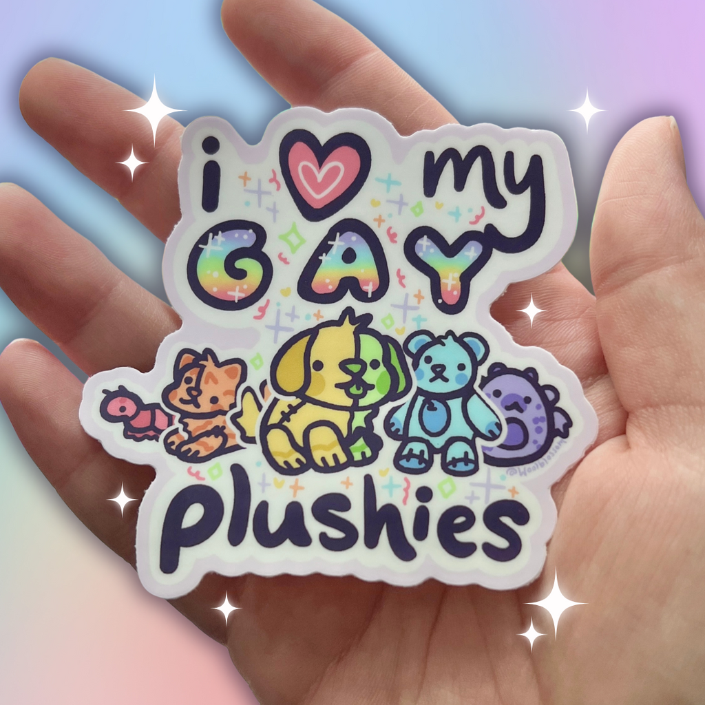 Hand holding a Sticker with 'i ❤️ my GAY plushies' text and rainbow-colored plushies