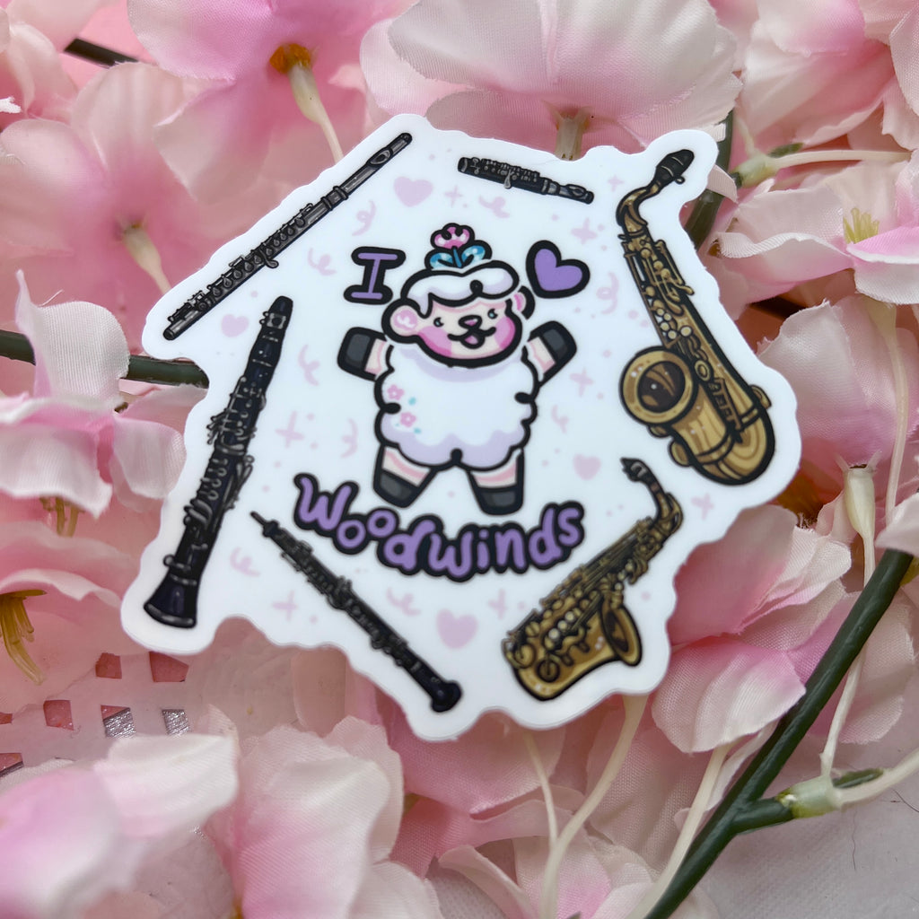 a sticker of a sheep with the text "I heart woodwinds" and six instruments floating around them (flute, piccolo, tenor sax, alto sax, oboe, clarinet)