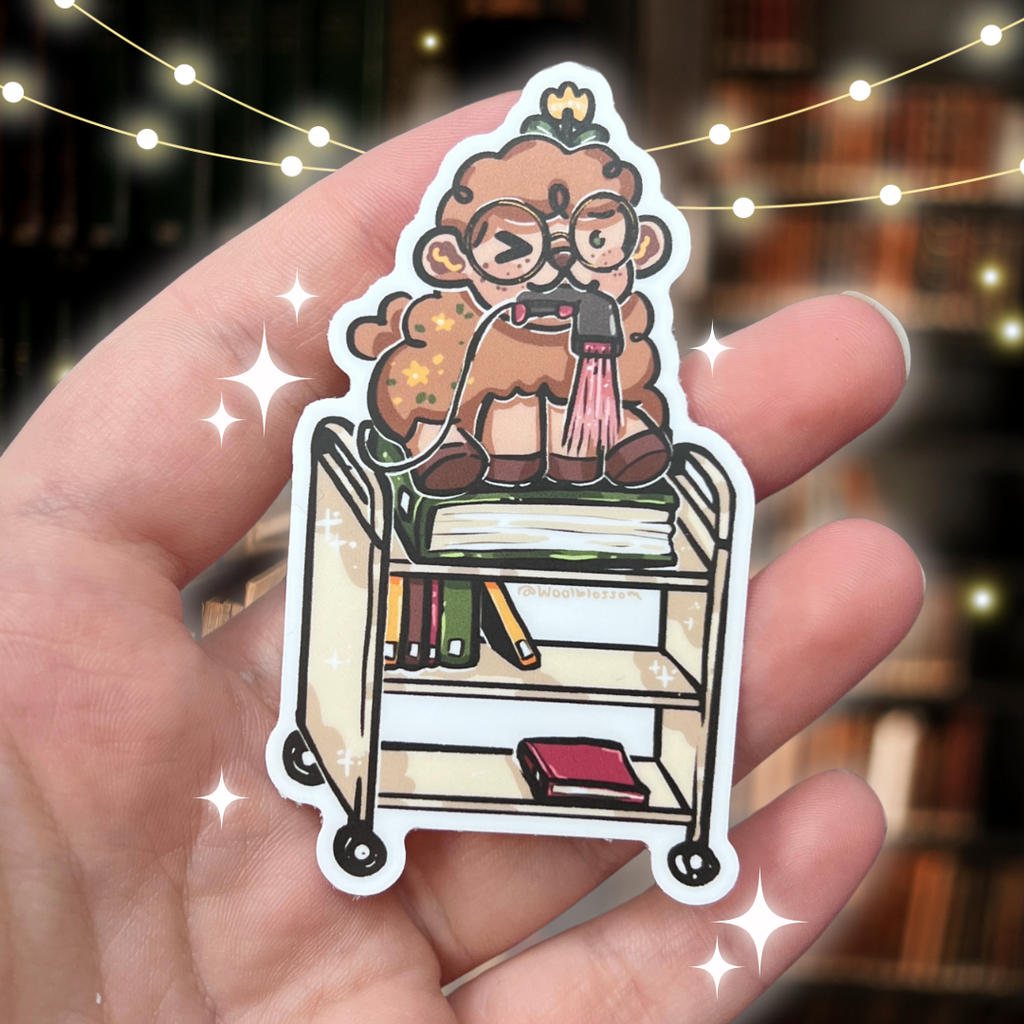 A sticker of Sage the sheep on top of a book cart with a scanner in his mouth