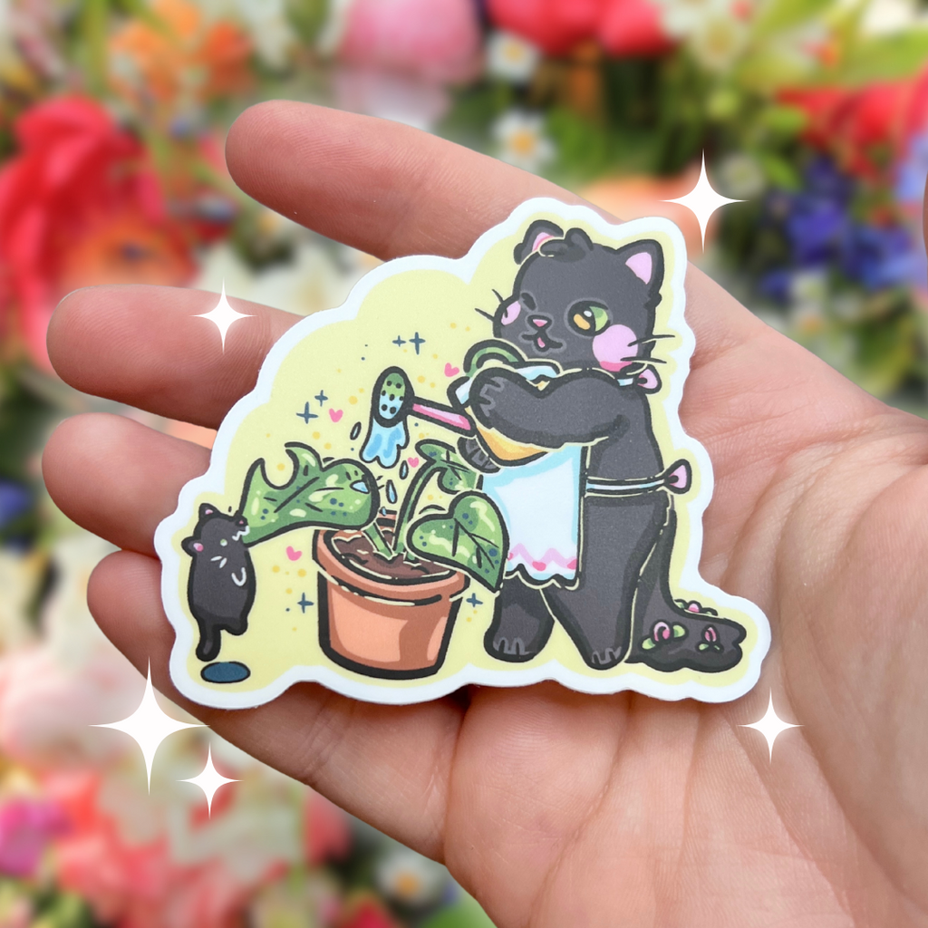 A sticker of a black cat with pink details in its ears, nose, and cheeks as well as little pink flowers in its tail, wearing a white apron, and using a watering can to water a leafy plant in a pot. A tiny black kitten is hanging off the ground, biting one of the leaves