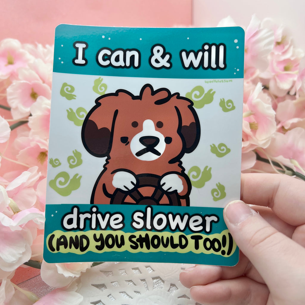 a bumper sticker of a dog driver with a determined expression and surrounded by tiny snails, with text that says "i can and will drive slower (and you should too!)"