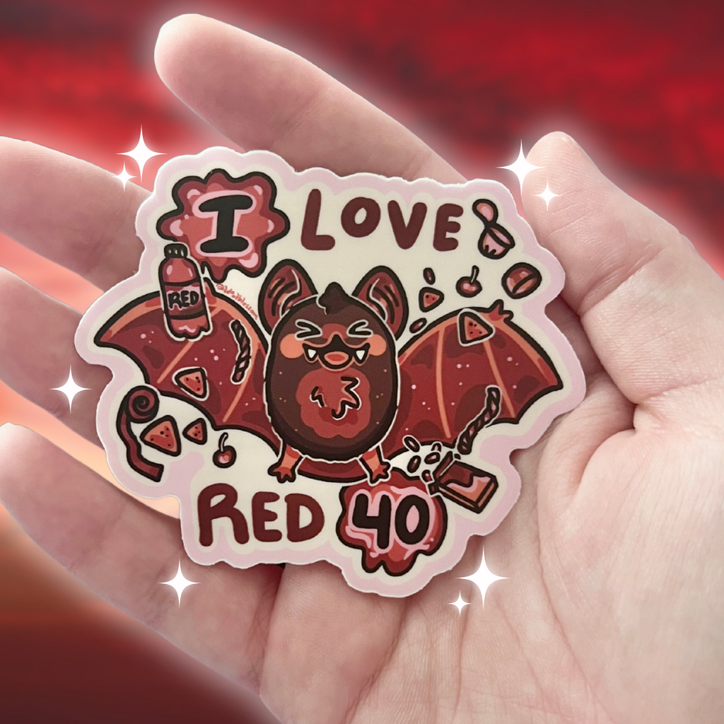 Sticker with a bat design and 'I love Red 40' text held in a hand against a red background.