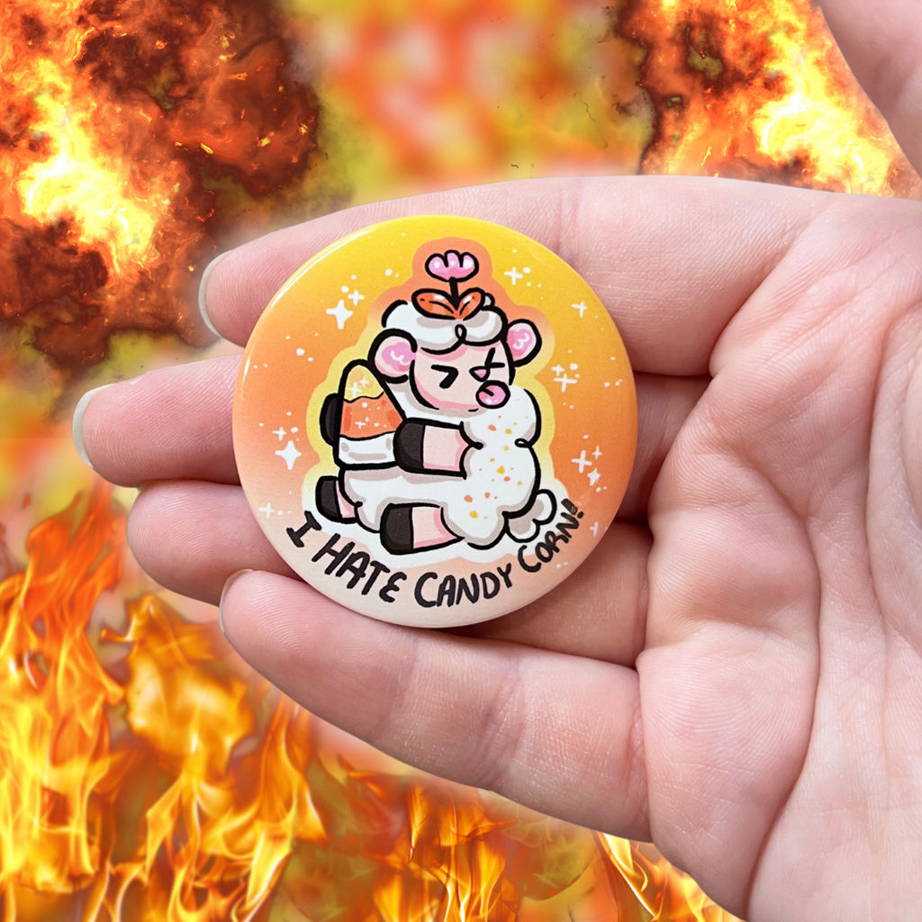 A button of a sheep holding a candy corn, sticking its tongue out, with the text "I hate candy corn!"