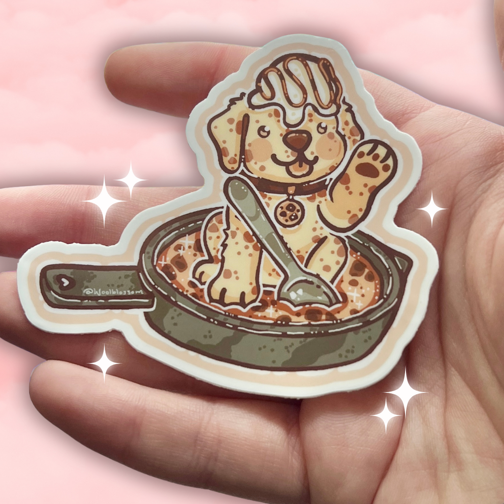 Sticker of a cookie dog on a cookie skillet in a hand 