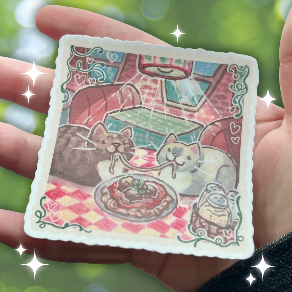 Hand holding a sticker of two cats eating spaghetti in a restaurant