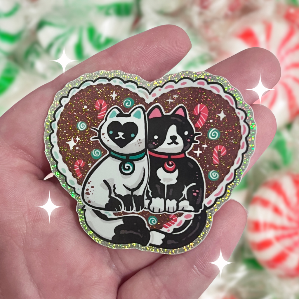 A sticker of two cats, one tuxedo, and one white with black markings, both are mint themed.