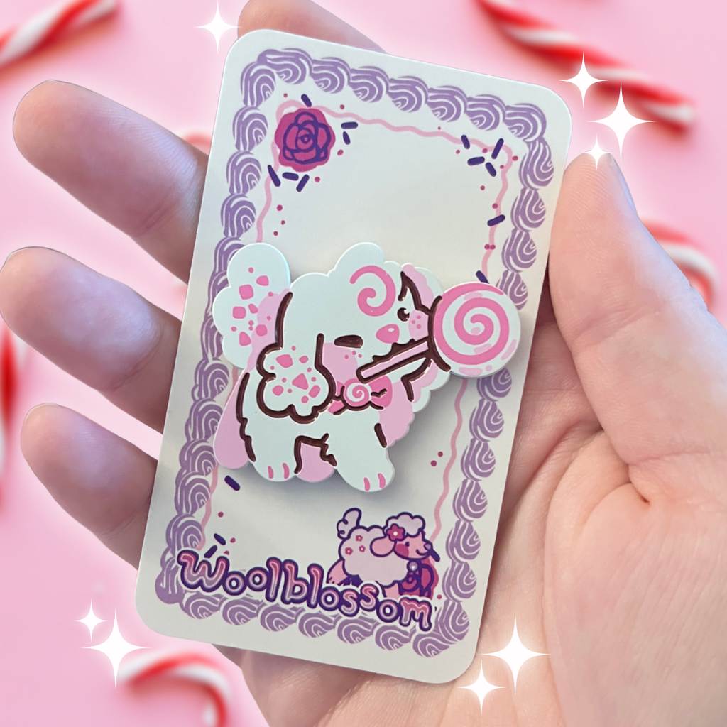 An enamel pin of a white and pink dog holding a candy cane lollipop in her mouth