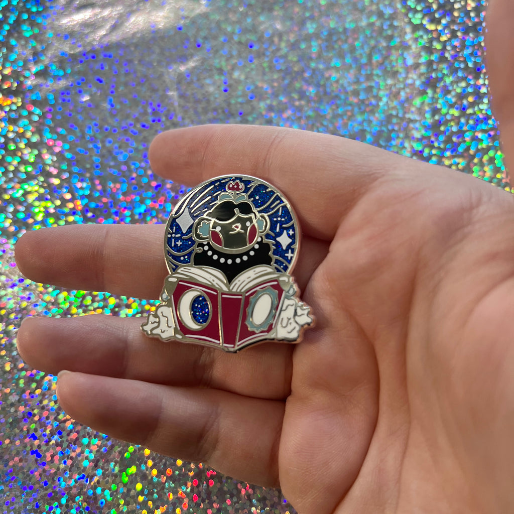 Hand holding the pin against a glittery background