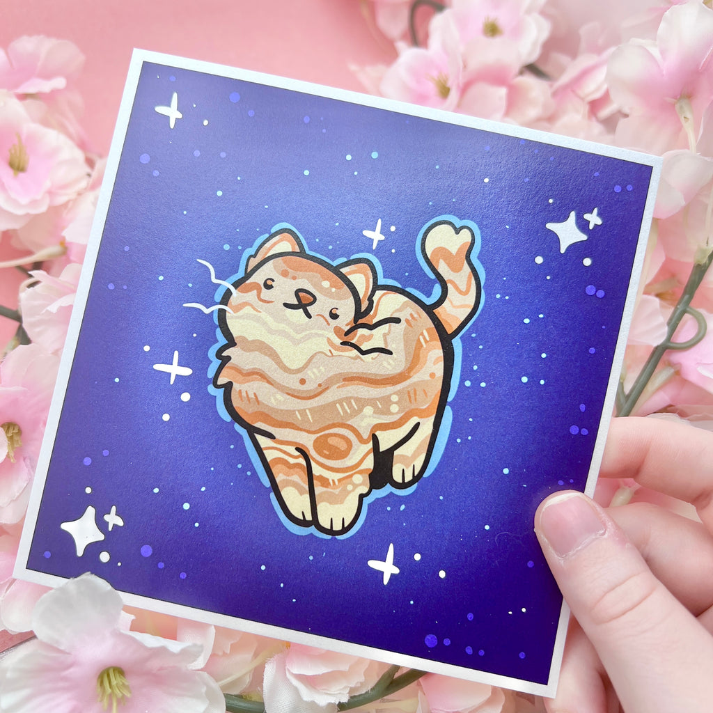 a print of an orange cat with markings like jupiter's on a dark blue background mimicking space