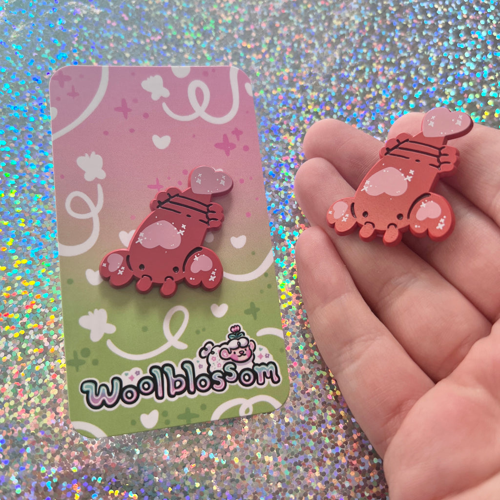 an enamel pin of a lobster with heart details