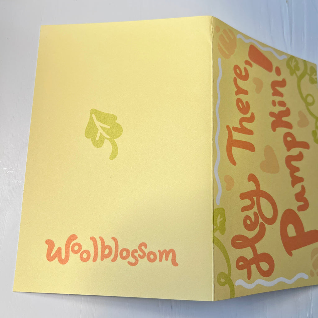 Yellow card with 'Hey There! Pumpkin!' and 'Woolblossom' text on a light gray background