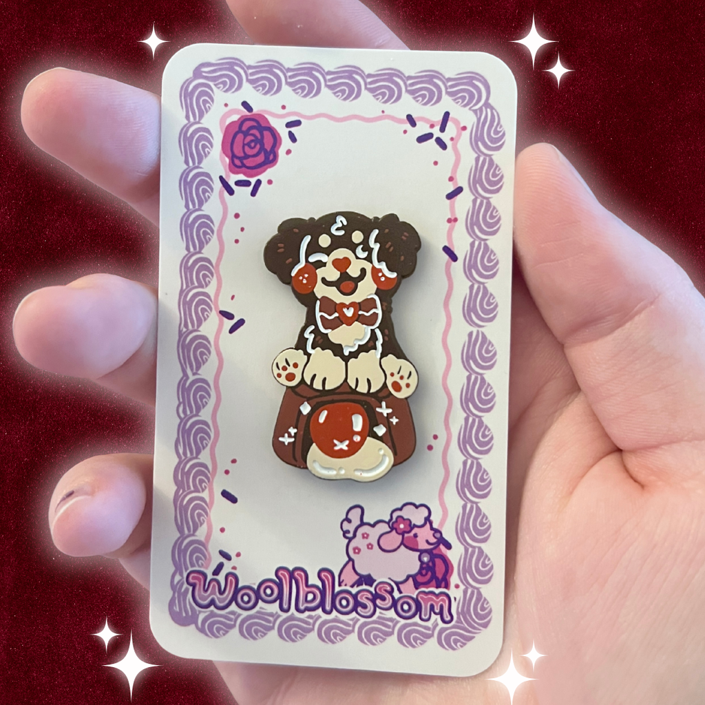 An enamel pin of a dark brown dog on top of a cherry cordial