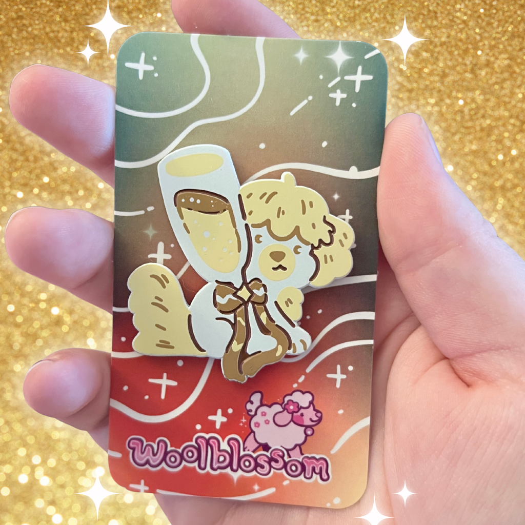 An enamel pin of a pale yellow dog behind a champagne glass