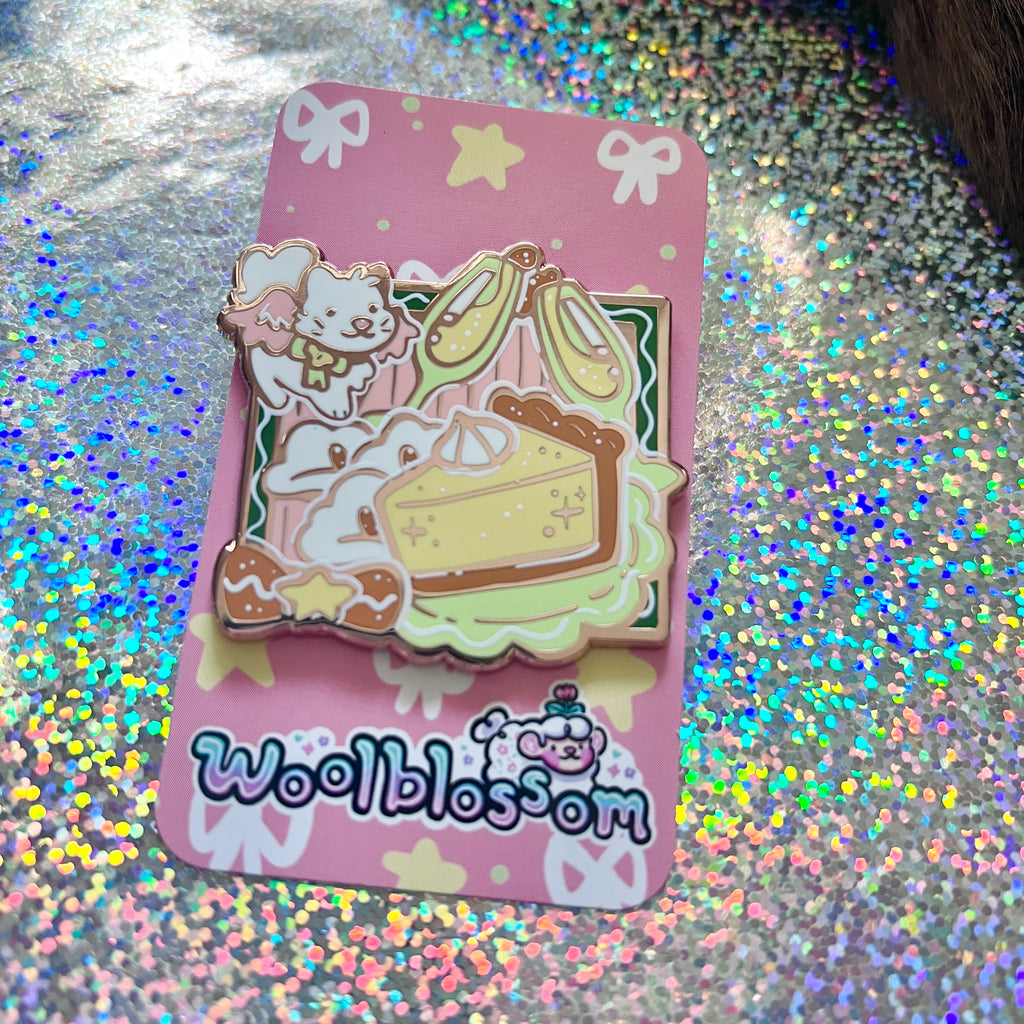 An enamel pin on a decorative card with 'woolblossom' branding on a glittery background