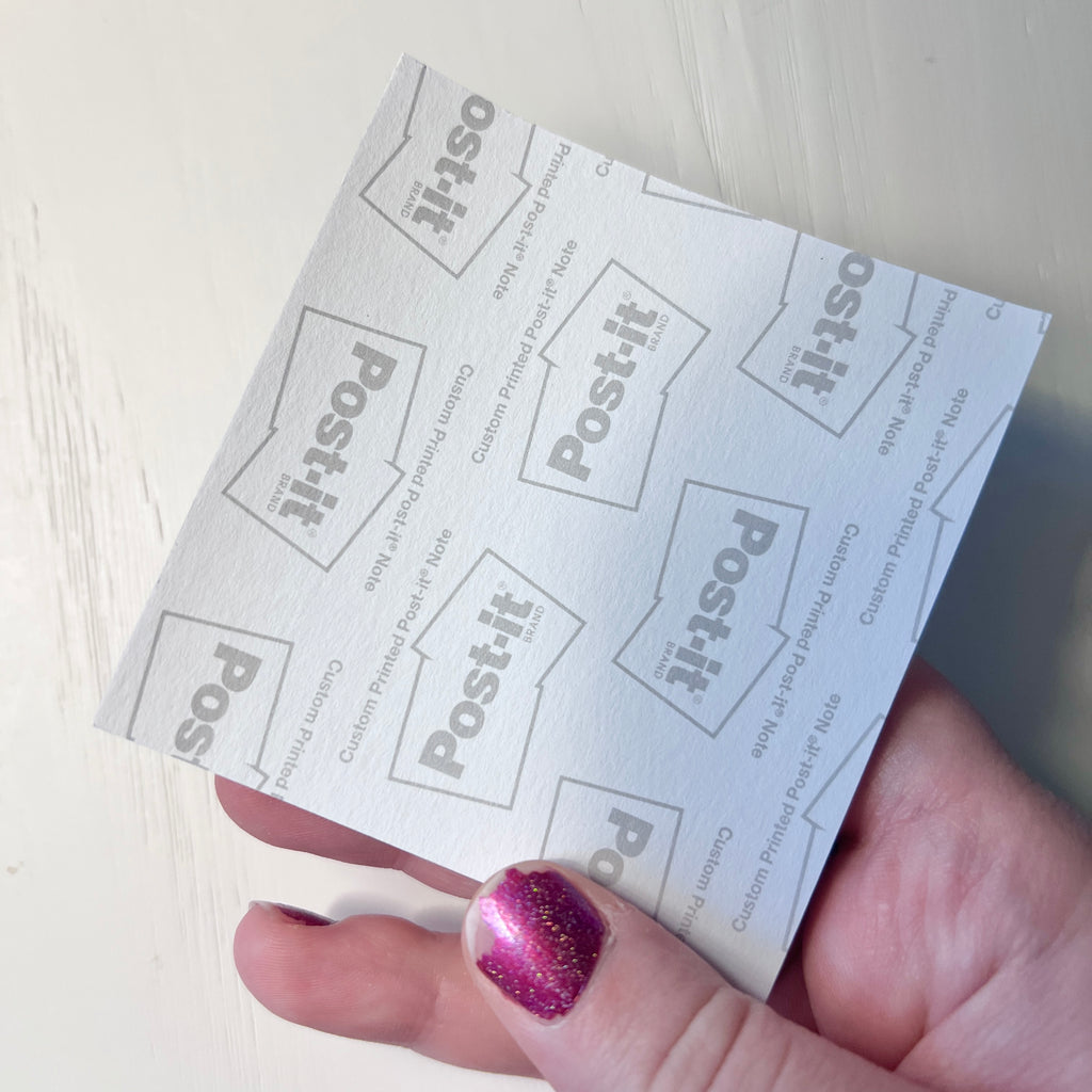 Hand holding a sheet of Post-it notes with a white background