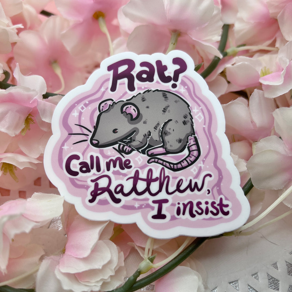 a sticker of a grey rat on a pink solid background with the text "Rat? Call Me Ratthew, I Insist"