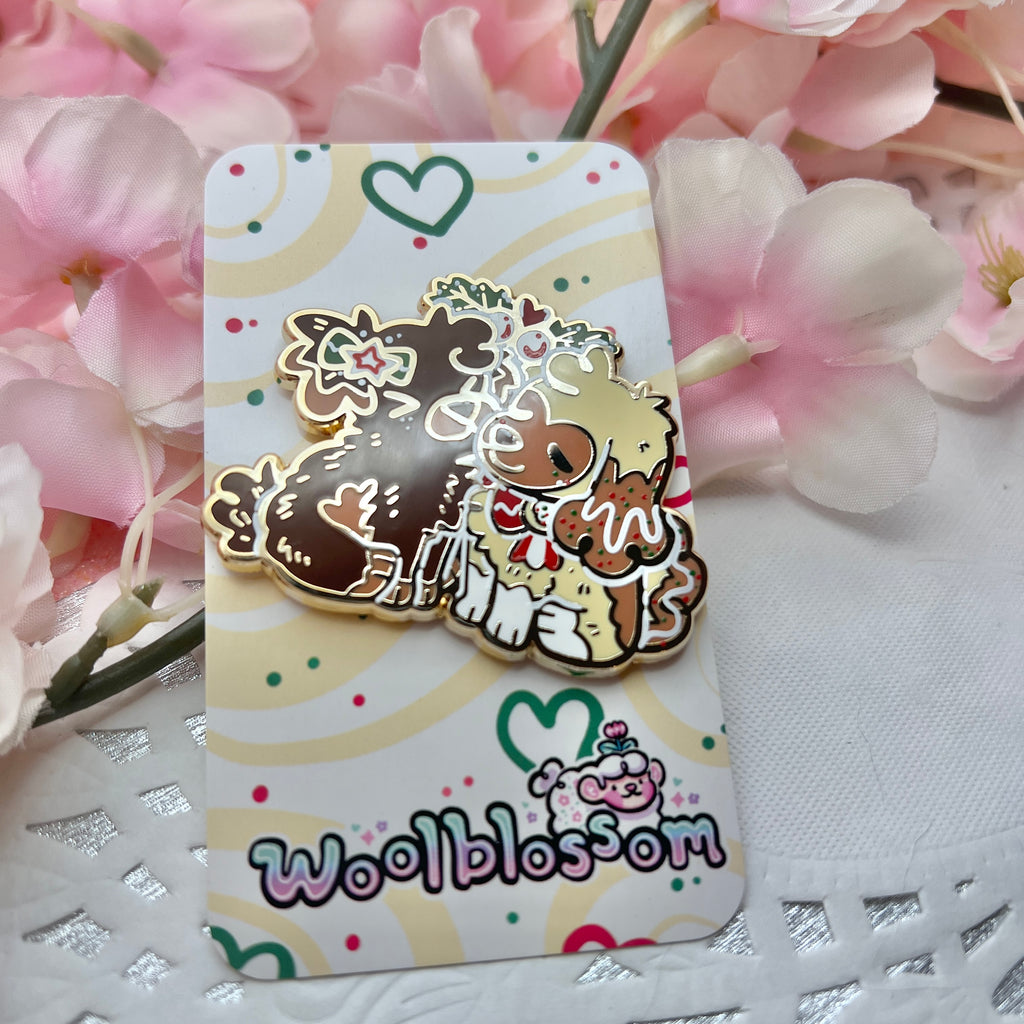 an enamel pin featuring Cinnamon, the Gingersnap puppy, and Caramel, the Sugar Cookie puppy, sharing a sweet mistletoe kiss