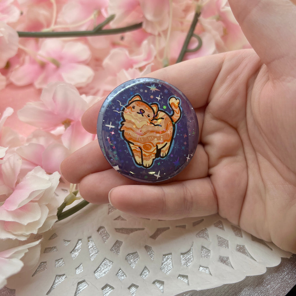 a button of an orange cat with markings like jupiter's