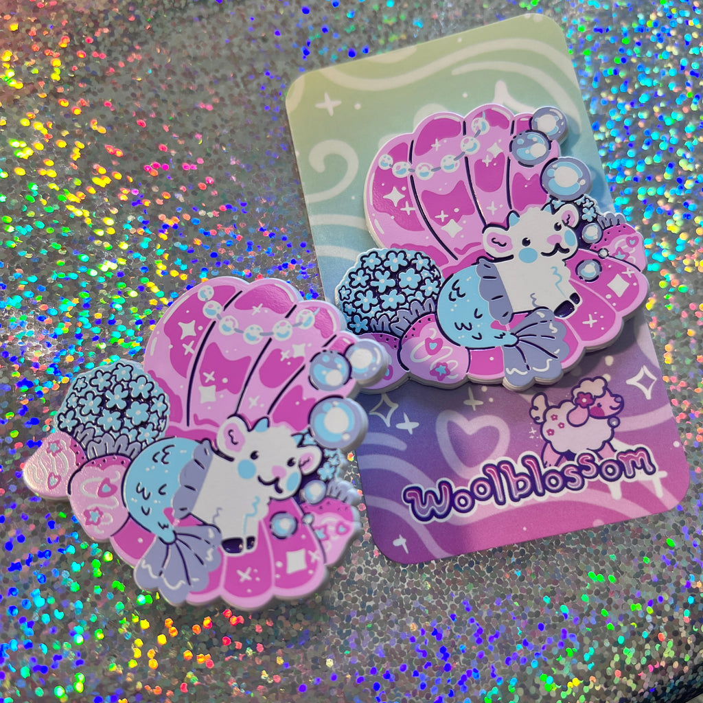 Enamel pin of a mermaid goat in a seashell on a glittery background