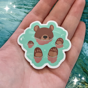 A sticker of a brown bear floating in river water