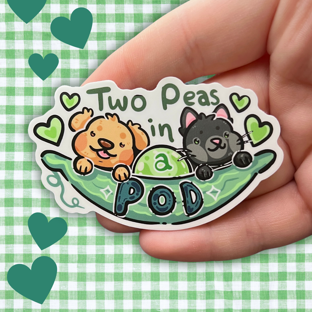 A sticker of a pea pod with a golden retriever and a black cat sticking out and text that says “two peas in a pod”