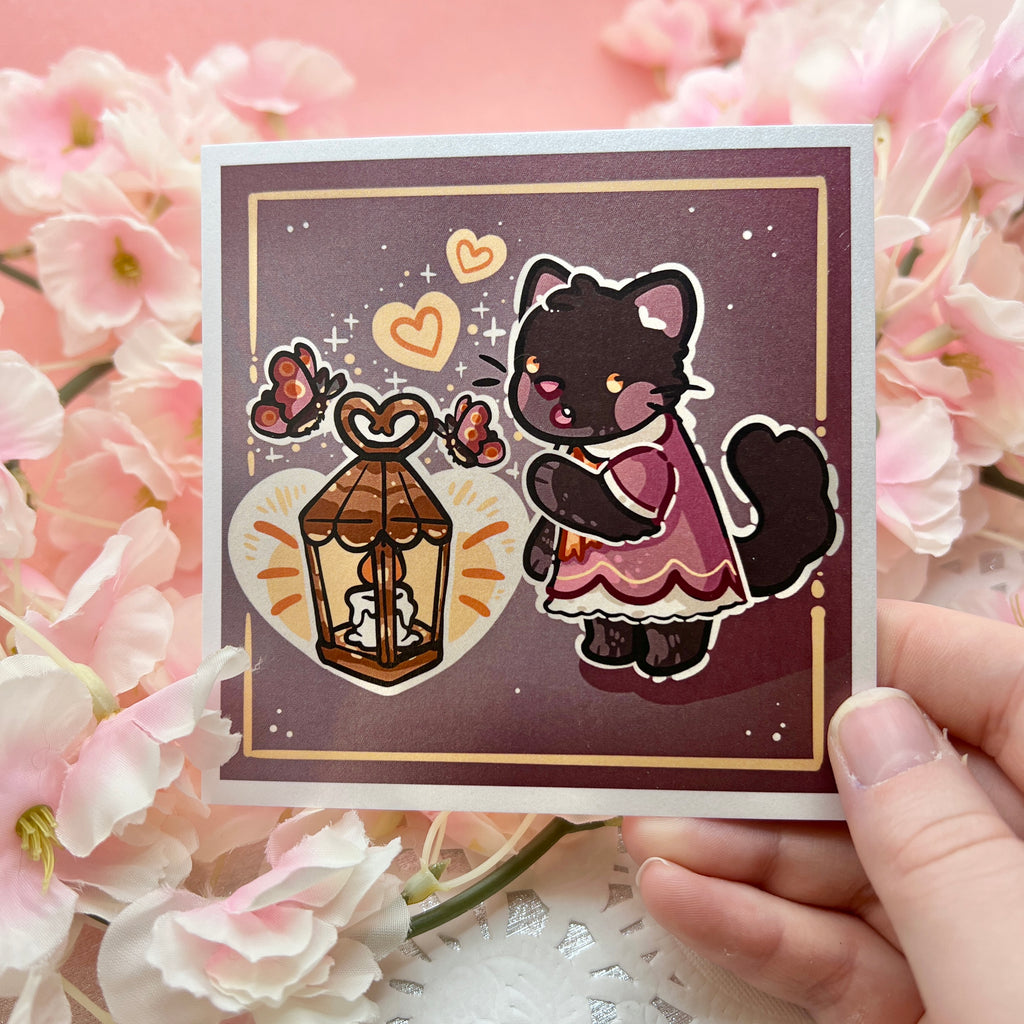 A print of a black cat in a dark rose pink dress reaching out in wonder at a lantern, moths around it, and a heart shape glow