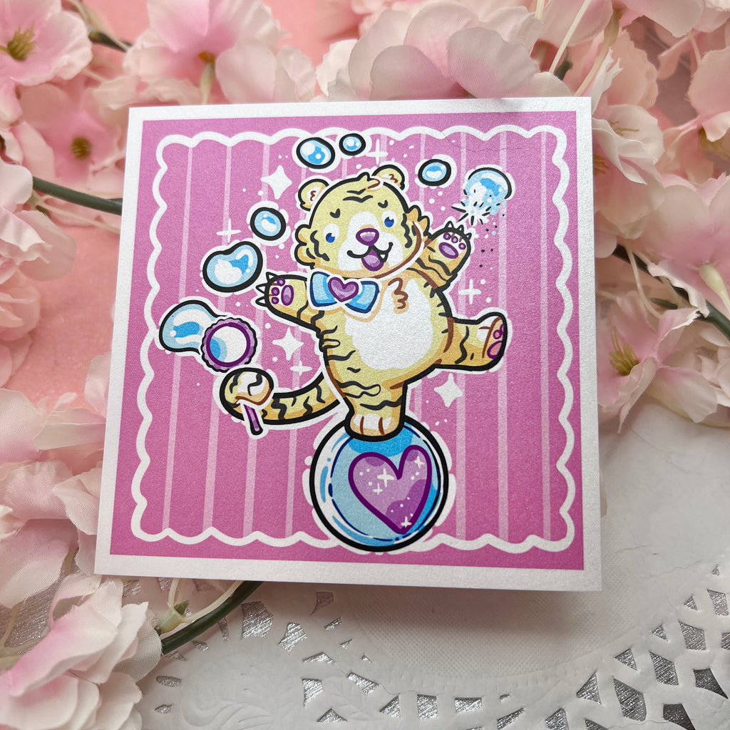 A print of a cute tiger balancing on a ball, bubble wand in tail, reaching up and poking the bubbles with his claws. Pink aesthetic overall.