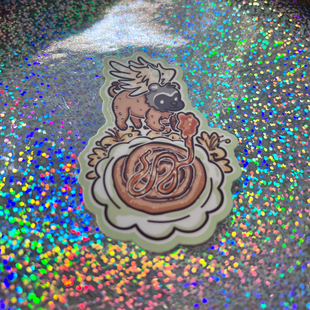 a sticker of a badger gryffin pouring honey over a cinnamon roll with honeysuckles on a glittery background