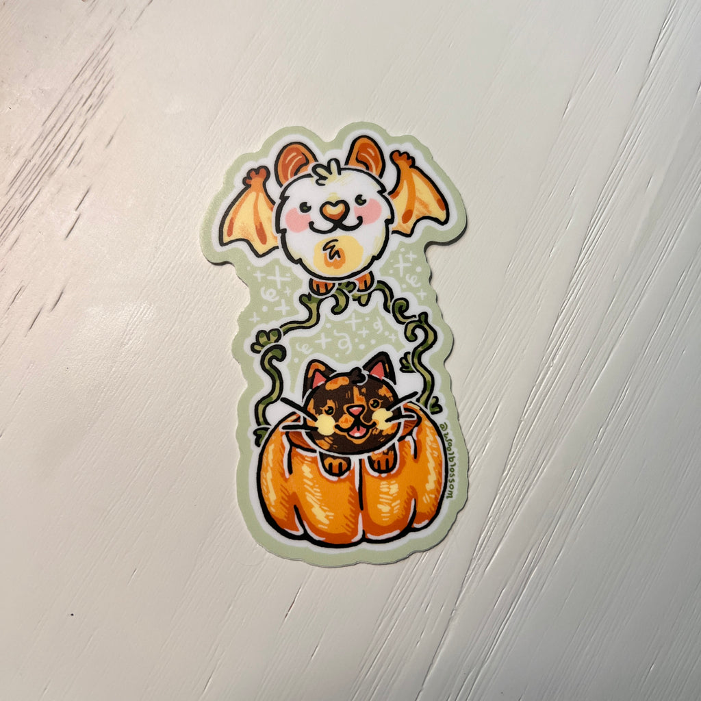 Halloween-themed sticker with a cat in a pumpkin and bat held by hands against a white background.