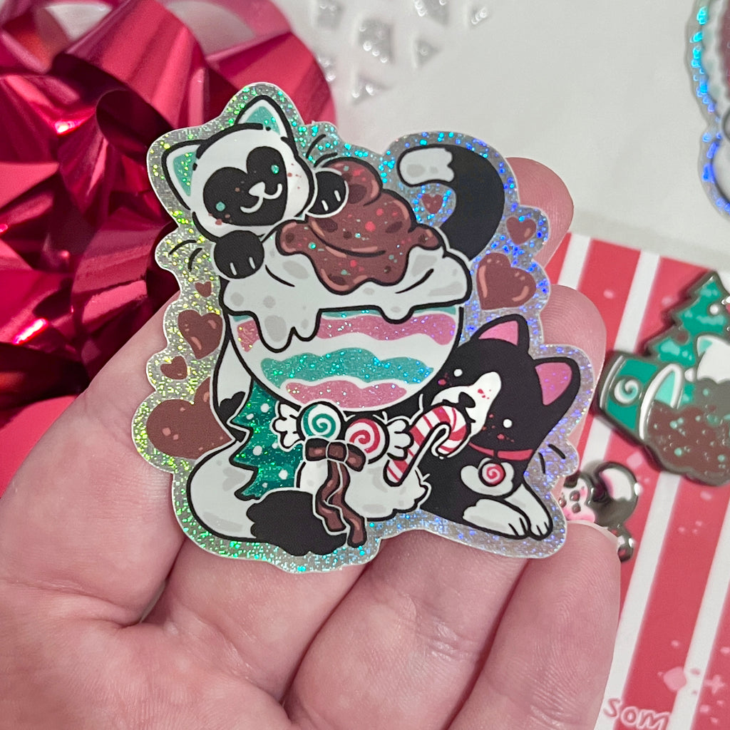 A sticker of two cats, one tuxedo, and one white with black markings, both are mint themed and eating a mint sundae