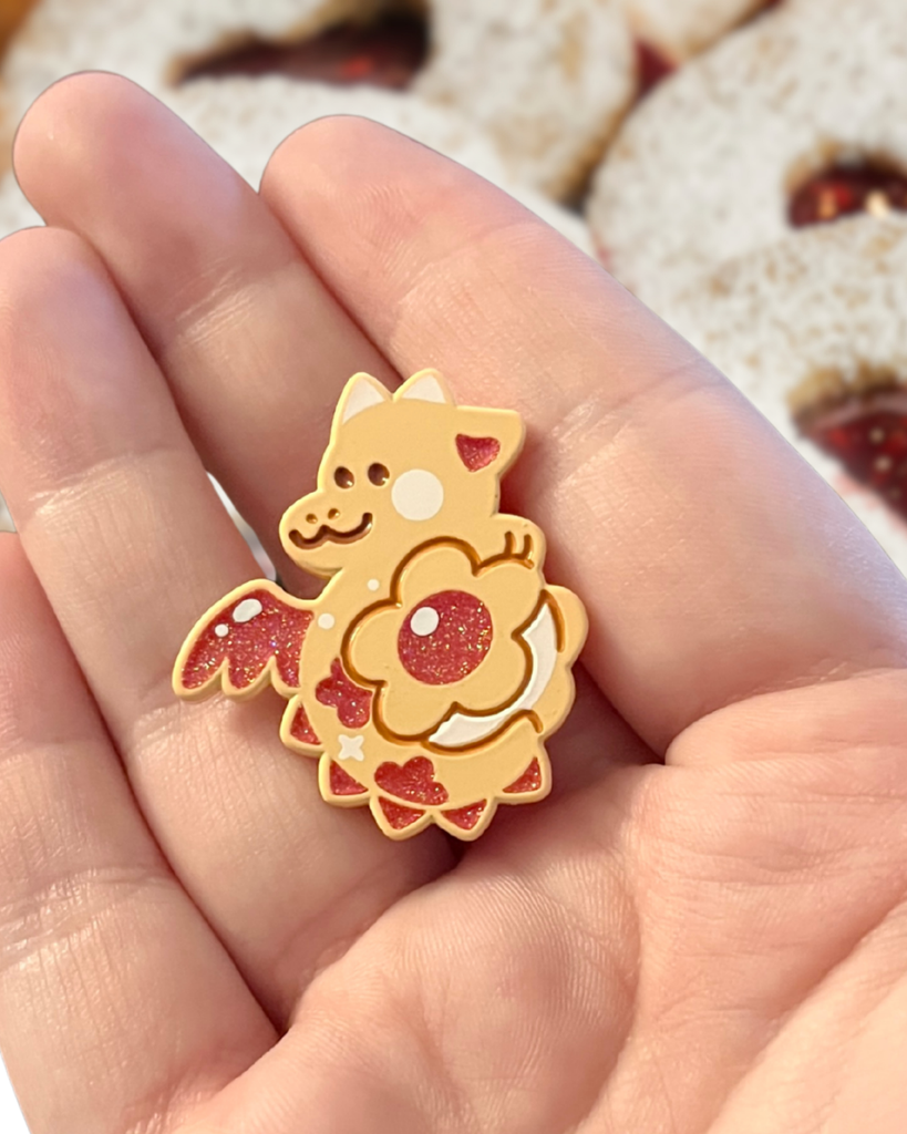 jammy cookie dragon pin held in a hand