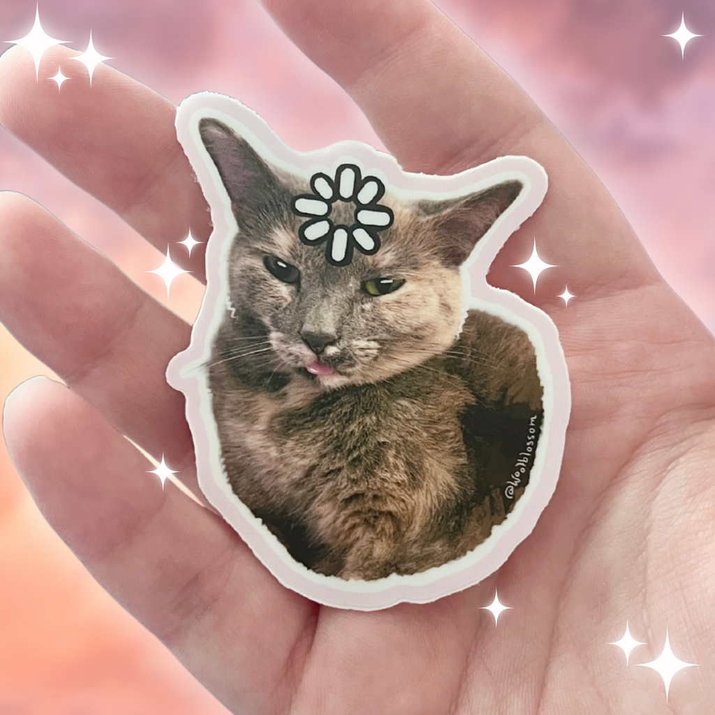 Cat-shaped sticker with a cat's face and buffering symbol on a hand with sparkly background